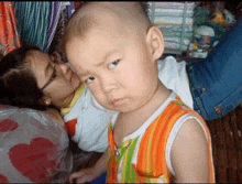 a little boy laying on a woman 's lap looks at the camera with a serious look on his face