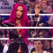 a woman with pink hair is in a wrestling ring with a sign that says all on asha