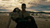 a man is holding a woman in his arms in the desert .