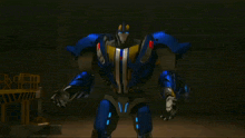 a blue robot with a yellow stripe on its chest is standing with its arms outstretched