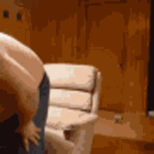 a man without a shirt is bending over in front of a couch .