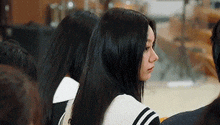 a woman with long black hair is sitting next to another woman in a crowd of people .