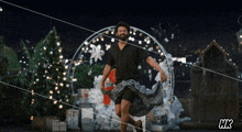 a man in a black shirt is dancing in front of christmas trees