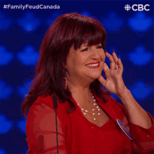 a woman in a red dress is applauding in front of a microphone with a cbc logo behind her