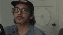 a man with a mustache is standing in front of a shure microphone