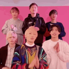 a group of young men are standing next to each other and clapping .