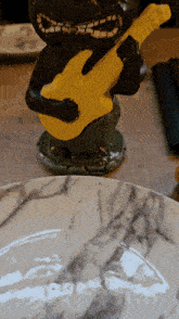 a statue of a man holding a yellow guitar on a table