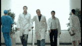 a group of doctors are walking down a hallway with a man with crutches