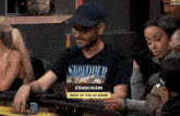 a man wearing a shirt that says shredder sits at a table