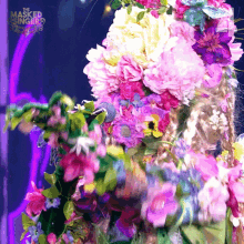 a masked singer is surrounded by pink flowers