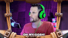 a man wearing green headphones is talking into a microphone and says oh my gosh .