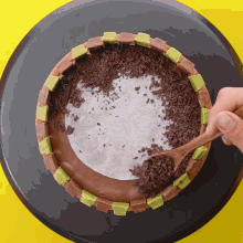 a person is using a wooden spoon to spread chocolate chips on a cake