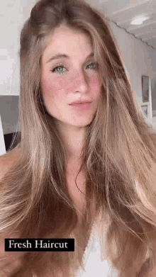 a woman with long brown hair and blue eyes is wearing a white tank top .