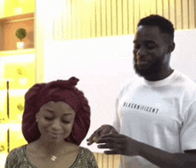 a man and a woman are standing next to each other and the man is wearing a shirt that says blacknificent .