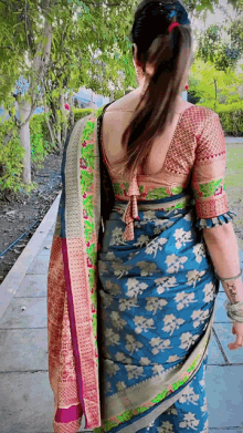 a woman is wearing a blue saree and a red blouse .