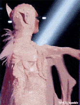 a woman in a white dress with feathers on her wings is dancing in front of a light that says tumblr on the bottom