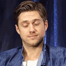 a man in a denim shirt is making a funny face with his eyes closed