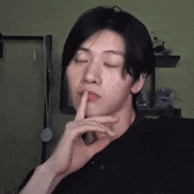 a young man with his eyes closed and his finger on his lips