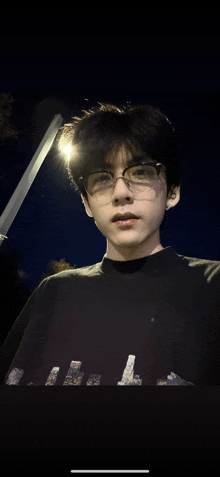 a young man wearing glasses and a black sweater with the letter l on it