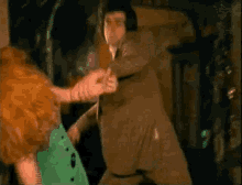 a man in a brown suit is holding a woman 's hand
