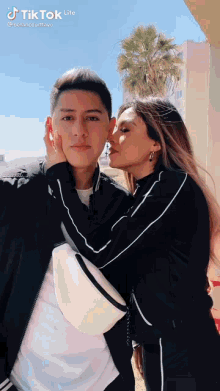 a woman is kissing a man on the cheek in a tiktok video .