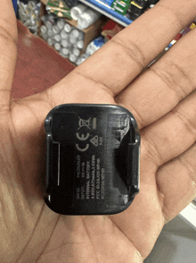 a hand is holding a small black device that says ' ce ' on it
