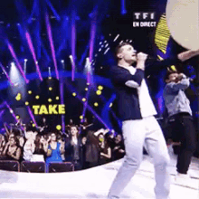 a man singing into a microphone in front of a crowd with the word take in the background