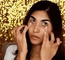 a woman with a nose ring is applying makeup to her face