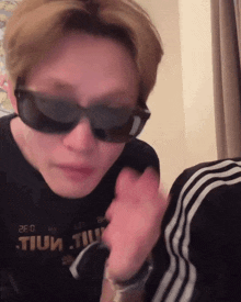a person wearing sunglasses and a shirt that says tium