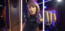 a woman is pointing at the camera while singing into a microphone .