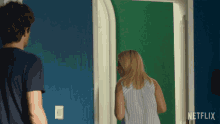 a man and a woman are standing in front of a green door that says netflix on the door