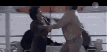 a couple of people are standing next to each other and fighting on a boat .