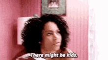 a woman with curly hair is sitting in a pink room and says `` there might be kids '' .