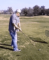 a man is swinging a golf club at a ball on a golf course