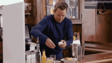 a man in a blue sweater is cracking an egg on a kitchen counter