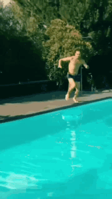 a shirtless man is jumping into a pool