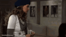 a woman wearing a blue beret is holding a badge that says ' sitemalperroni ' on it