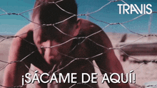 a man is behind a barbed wire fence with the words travis in white letters