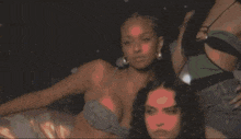 two women are standing next to each other and one has a necklace with the letter s on her chest