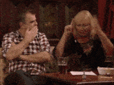 a man and a woman sit at a table with a glass of beer in front of them