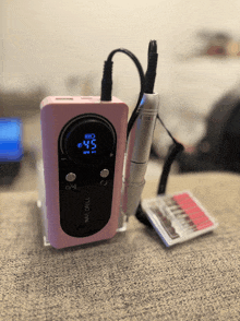 a pink nail drill sitting on a gray surface
