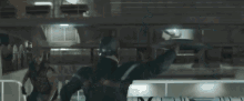 captain america is holding a shield in his hands while standing on a balcony .