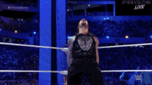 roman reigns is standing in a wrestling ring with his mouth open and screaming .