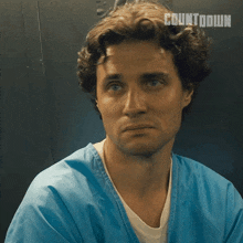 a man in a blue scrub is sitting in front of a countdown sign