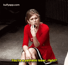 a woman in a red dress is sitting on the ground talking on a cell phone and asking if she is a pathetic loser