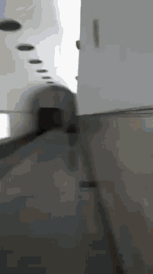 a person is walking down a long hallway in a building with a handrail .