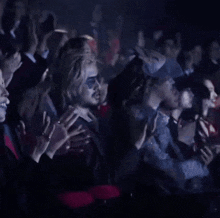 a crowd of people are sitting in a dark room applauding