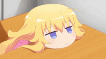 a little girl with blonde hair and blue eyes is laying on a wooden table