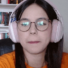 a woman wearing glasses and headphones has a reflection of a bookshelf in her glasses