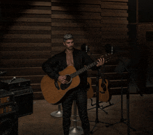a man playing an acoustic guitar in front of a microphone that says fender on it